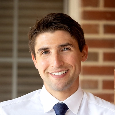 Dentist Evan Fry Smiling In Front Of Brick Wall