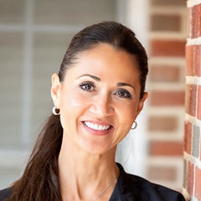 Registered Dental Hygienist Olga Smiling In Front Of Brick Wall